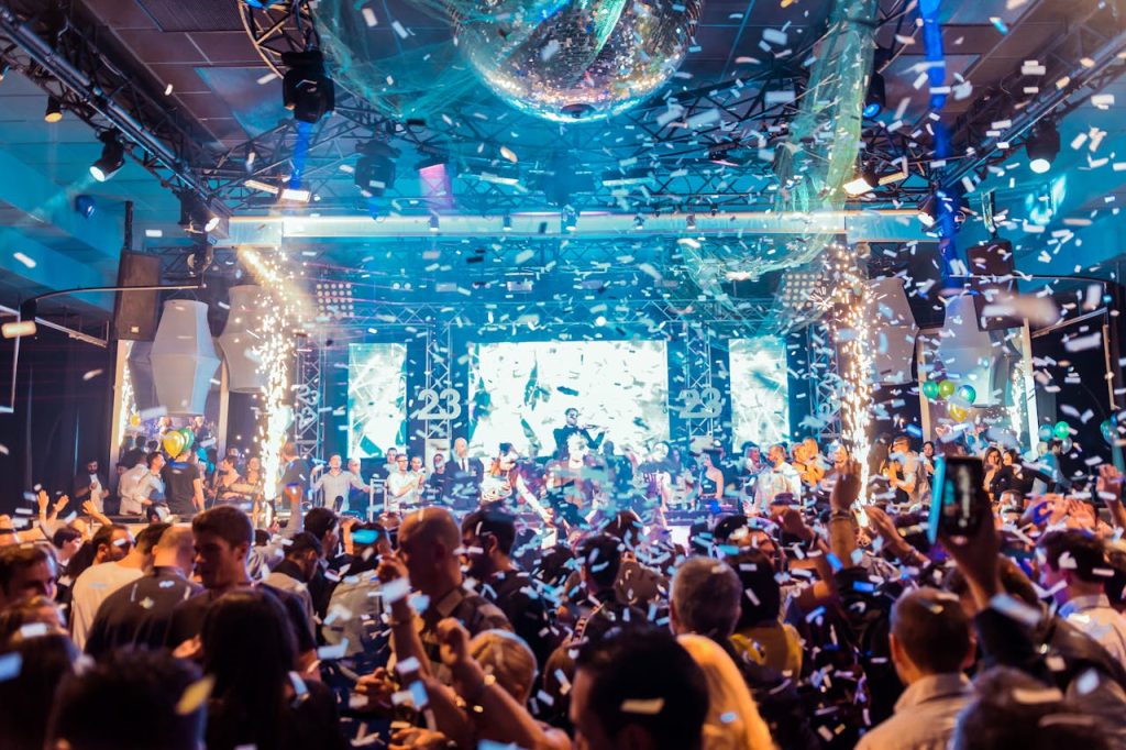people-at-a-party-3249760 Vibrant nightclub scene in Mantua, Italy, featuring a lively crowd, confetti, and colorful lights.