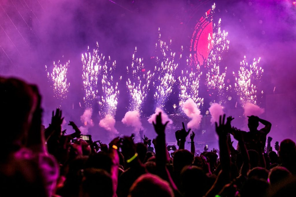 purple-fireworks-effect-1190298 Vibrant EDM concert scene with fireworks, smoke, and enthusiastic crowd enjoying the music.